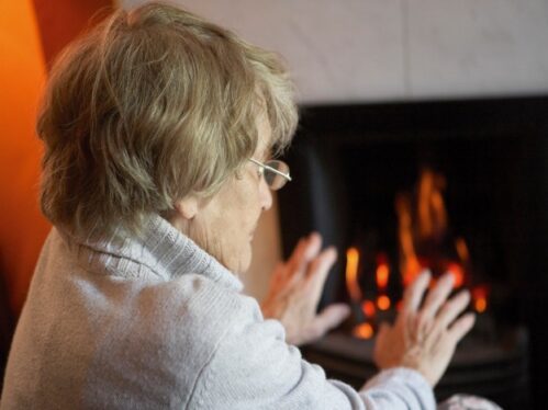 Old lady with hands by fire